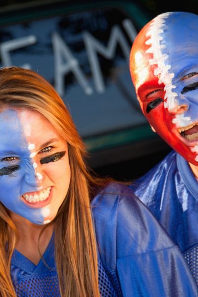 a man and woman with their faces painted with the colors of their favorite football team