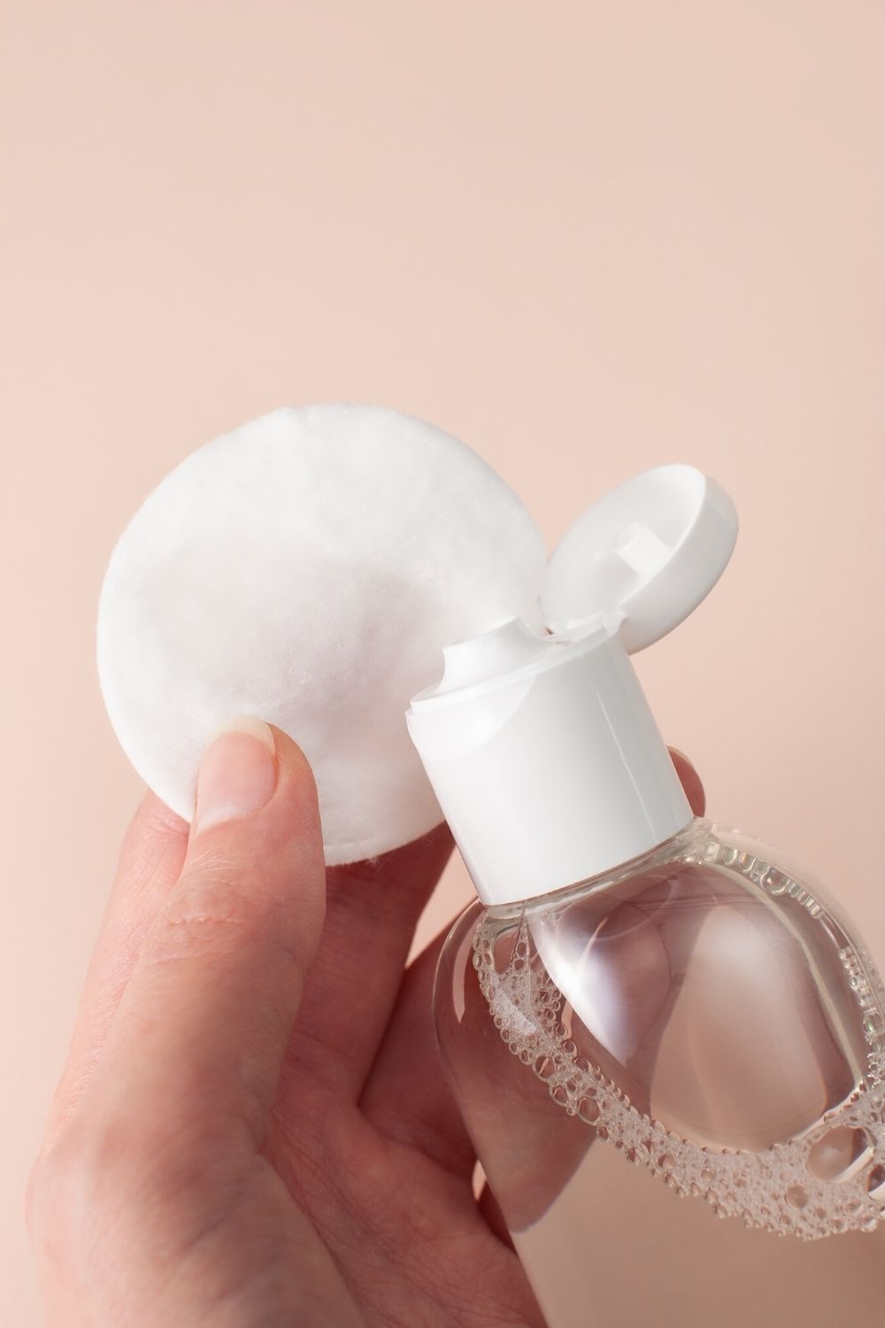 micellar water being squirted onto a cotton pad for removing face paint